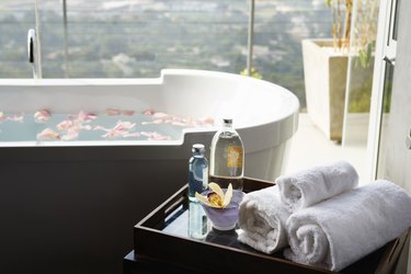 Towels, aromatic oils and orchid next to bathtub