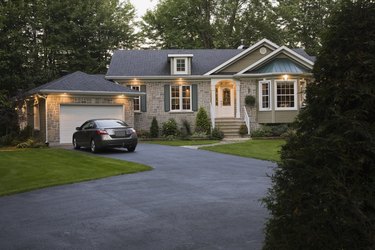 Brown, beige and gray stone residential home and landscaped front yard illuminated at dusk, Quebec, Canada. This image is property released. CUPR0215