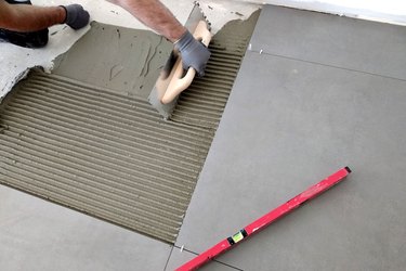 Worker hands putting ceramic tiles on the floorl.