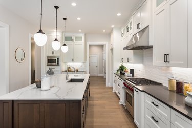 beautiful kitchen in new luxury home with island, pendant lights, and glass fronted cabinets