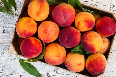 Fresh organic peaches in wooden crate.
