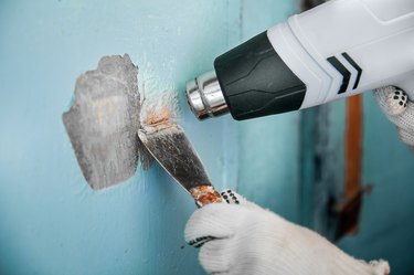 Master removes old paint concrete wall heat gun and scraper