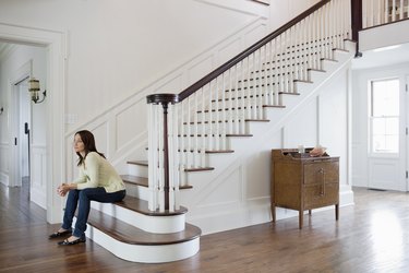 Mid adult woman sitting on stairs in entrance hall