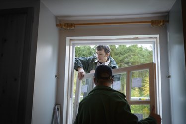 Father and son builders installing new window in house