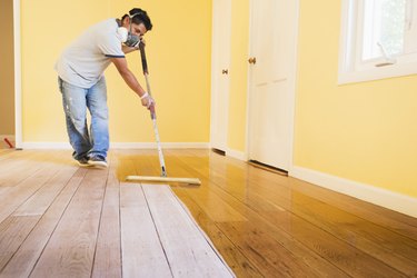 Hispanic man refinishing floors in new house