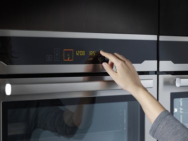 Woman using oven in domestic kitchen