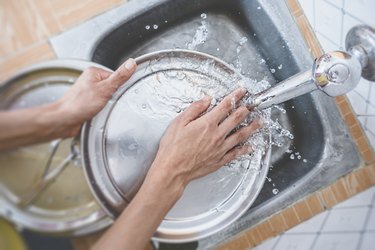 Cropped Hands Of Woman Washing Dishes In Kitchen Sink