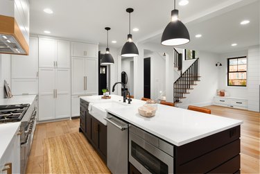 Beautiful white kitchen with dark accents in new farmhouse style luxury home