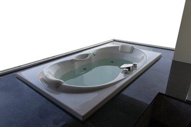 Empty white massaging jetted bathtub with sea and boats background