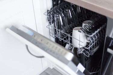 open dishwasher with clean glasses and dishes