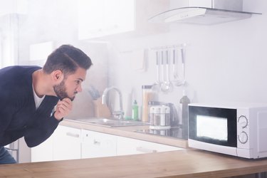 Man Spraying Fire Extinguisher On Microwave Oven