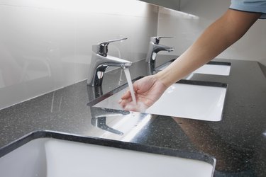 Cropped Hand Of Woman Washing Hand In Bathroom Sink