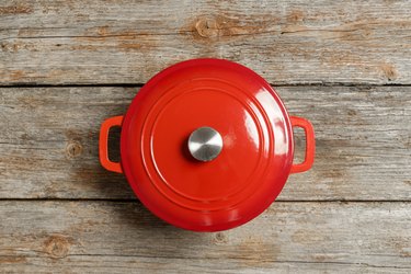 Top view of red enameled iron stockpot on wooden background