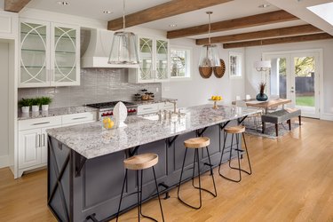 beautiful kitchen with lights off in new luxury home with island, pendant lights, and glass fronted cabinets, and view of dining room