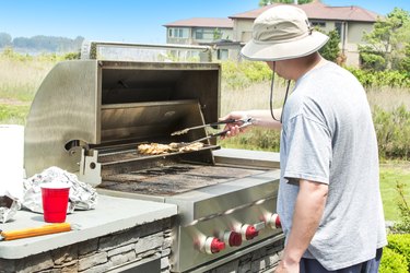 Man barbecuing chicken on a outdoor gas grill