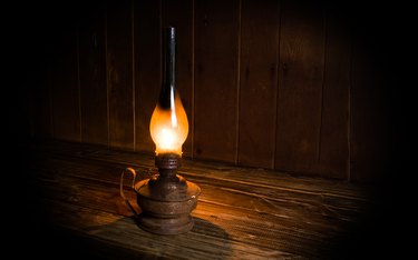 Antique burning paraffin lamp near on the wooden table.