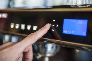 Finger pushing digital button on coffee machine
