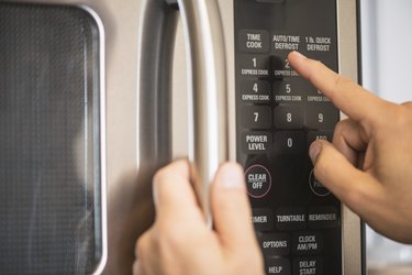 USA, New Jersey, Jersey City, Close-up of hand using microwave oven