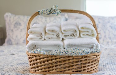 Close-Up Of Towels In Wicker Basket On Bed At Home
