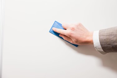 Hand of business man cleaning whiteboard.