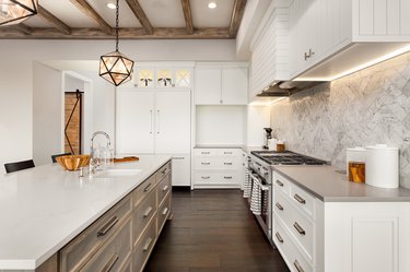 beautiful kitchen in new luxury home with island, pendant lights, and hardwood floors.