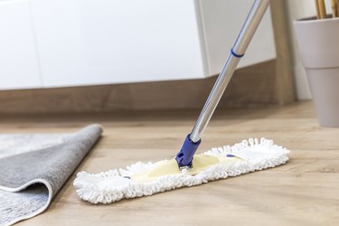Modern white mop being used for cleaning a wooden floor