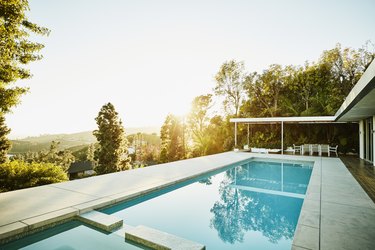 Pool in backyard of modern house at sunset