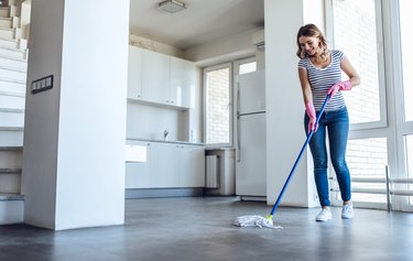 Young woman is doing cleaning of a laminate floor