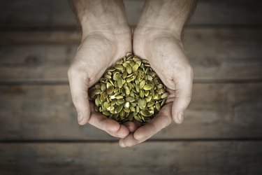 Pumpkin seeds in mans hands, close-up