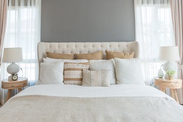 Bedroom in soft light colors. big comfortable double bed in elegant classic bedroom at home.