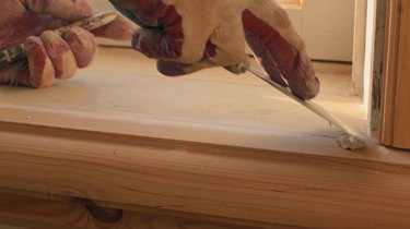 Man's hand puttied wooden frame of the window.