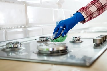 Young woman with washing fluid and rag washes and cleans in the kitchen. Cleaning concept