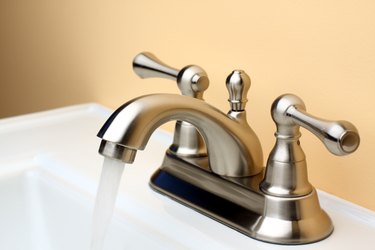 Water flowing from Brushed Nickel Faucet on Porcelain Bathroom Sink