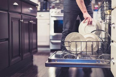 Midsection Of Man Keeping Plates In Dish Washer