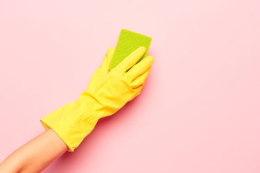 The woman's hand cleaning on a pink background. Cleaning or housekeeping concept