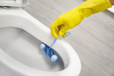 Putting toilet balls cleaner in toilet bowl