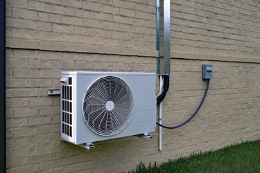 Air Conditioner mini split system next to home with brick wall