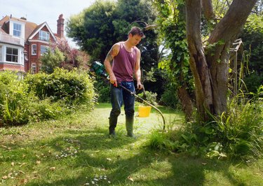 Man using a string strimmer in a yard or garden