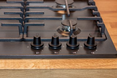 The control panel of the gas hob, the knob for adjusting the intensity of combustion of the gas stove burner. Black gas hob integrated into the wooden worktop