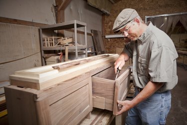 Carpenter uses chisel (tool) on cabinet drawer