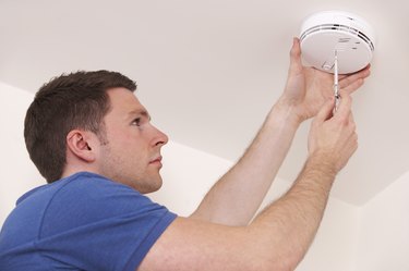 Man installing smoke or carbon monoxide detector.