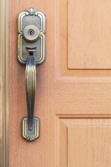 Antique metal door handle and brown wood door.