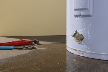 A residential domestic water heater leaking with plumber’s tools