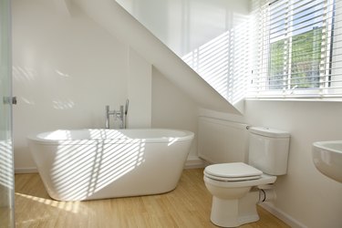 Modern white bathroom with tub, toilet, and sink.