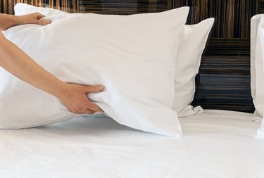 Placing pillow on bed.
