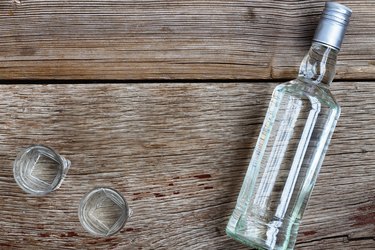 VODKA luxury. Vodka bottle with shot glasses on the Board. On wooden background.
