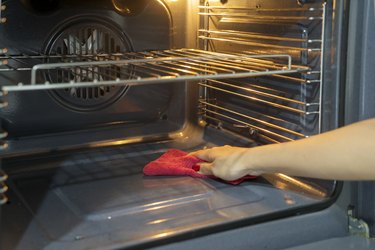 Cropped Hand Of Woman Cleaning Oven