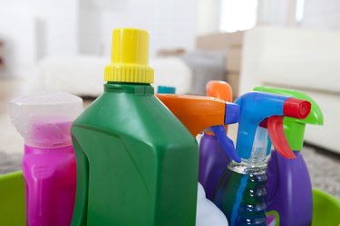 Colourful cleaning product plastic bottles and sprays on kitchen counter