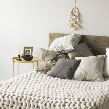 Bed with wooden headboard, pillows, knitted blanket. Scandinavian interior