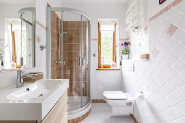Sink, toilet, and shower in small white bathroom with contrasting accents.